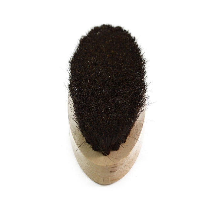 An oval shoe shine brush with horsehair bristles, with natural black bristles, wooden handle, on a white background.