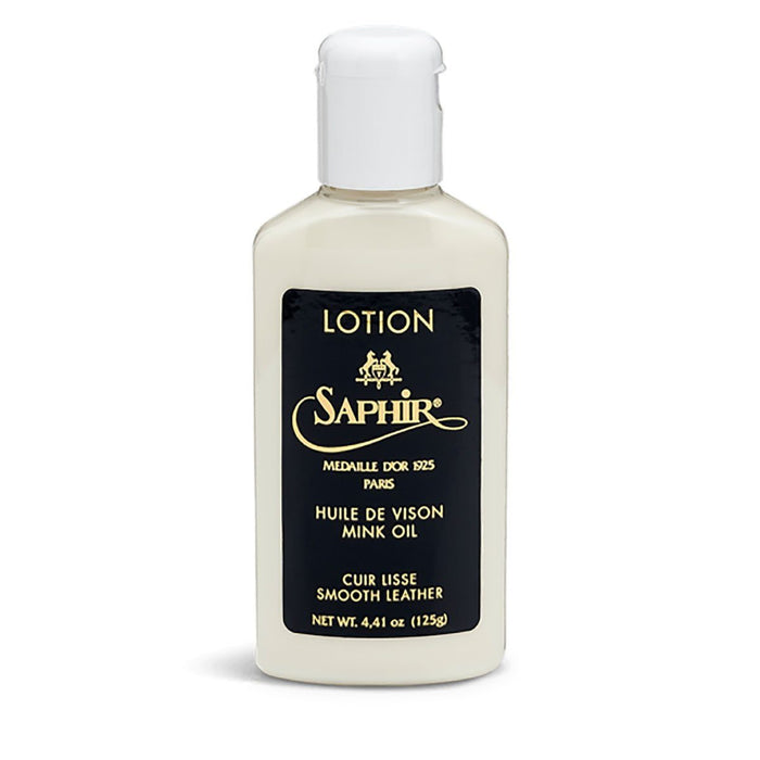 A white bottle with a flip cap lid labeled 'Saphir' and 'LOTION' for smooth leather, against a plain background.