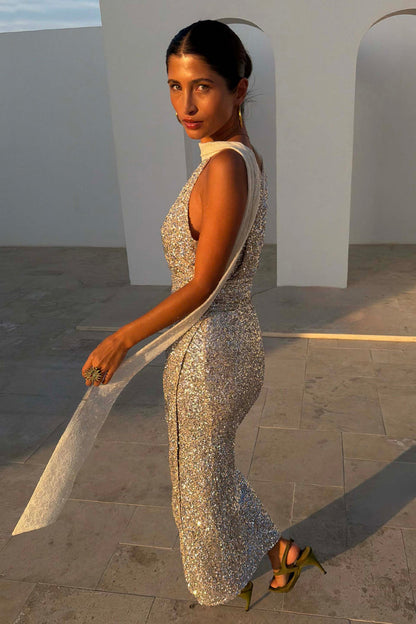 Silver Sequin Maxi Wrap Jaspre Skirt with a waist tie, styled in an outdoor architectural setting.