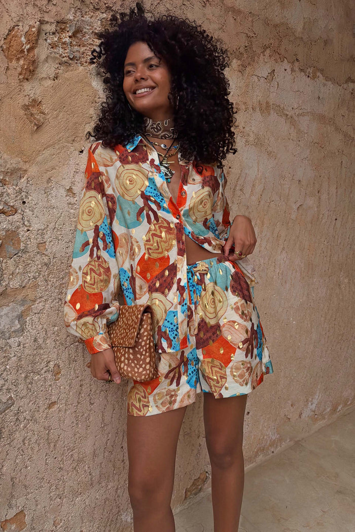 Shell Ellie Shorts in an abstract shell print with orange and blue tones, styled as a co-ord with a matching shirt.