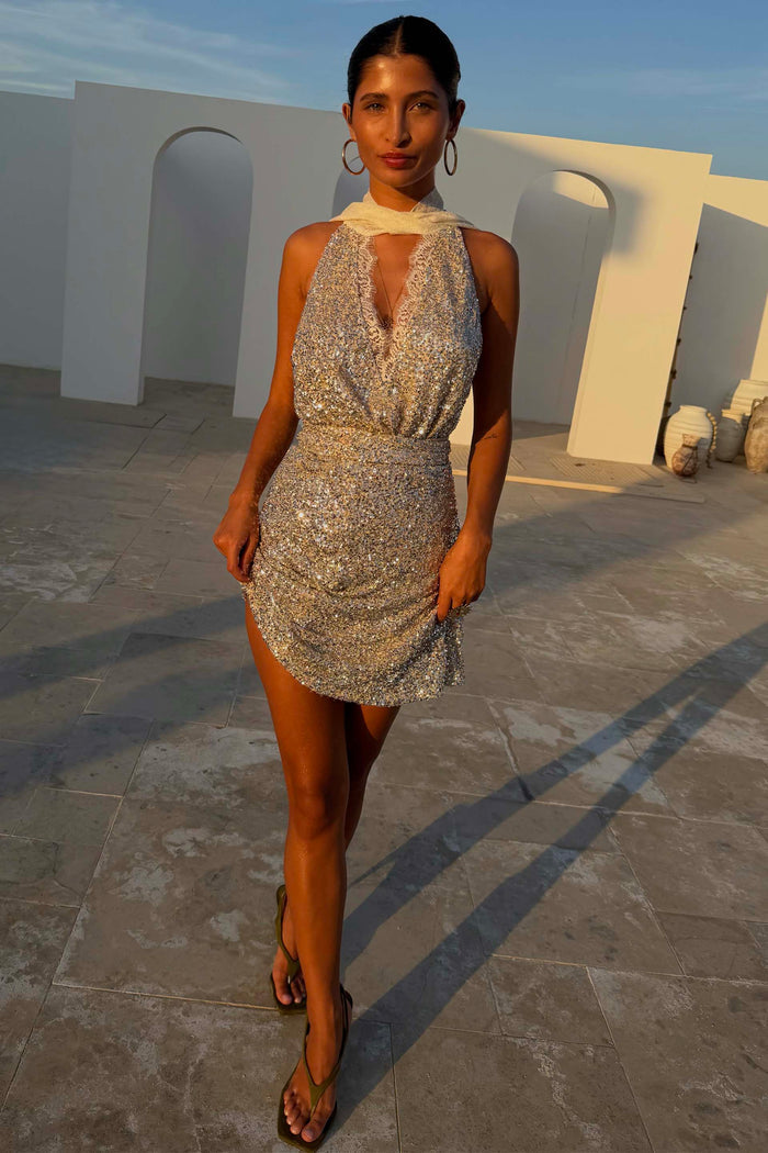 Silver Sequin Mini Jaspre wrap skirt with metallic discs on a model in a golden hour outdoor setting.