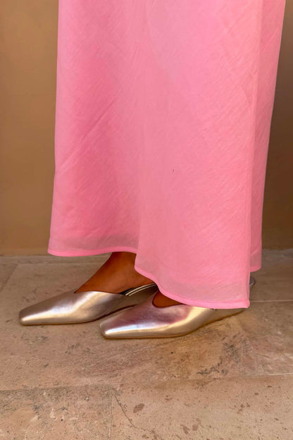 Silver Wedge Mule in metallic leather with a pointed toe and sculpted wedge heel, worn with a pink skirt.