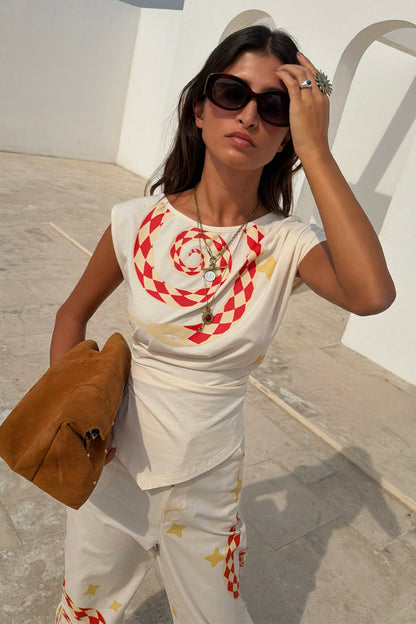 White cotton Snake Asymmetric Top with red snake print, star motifs and gathered waist, styled as a co-ord.