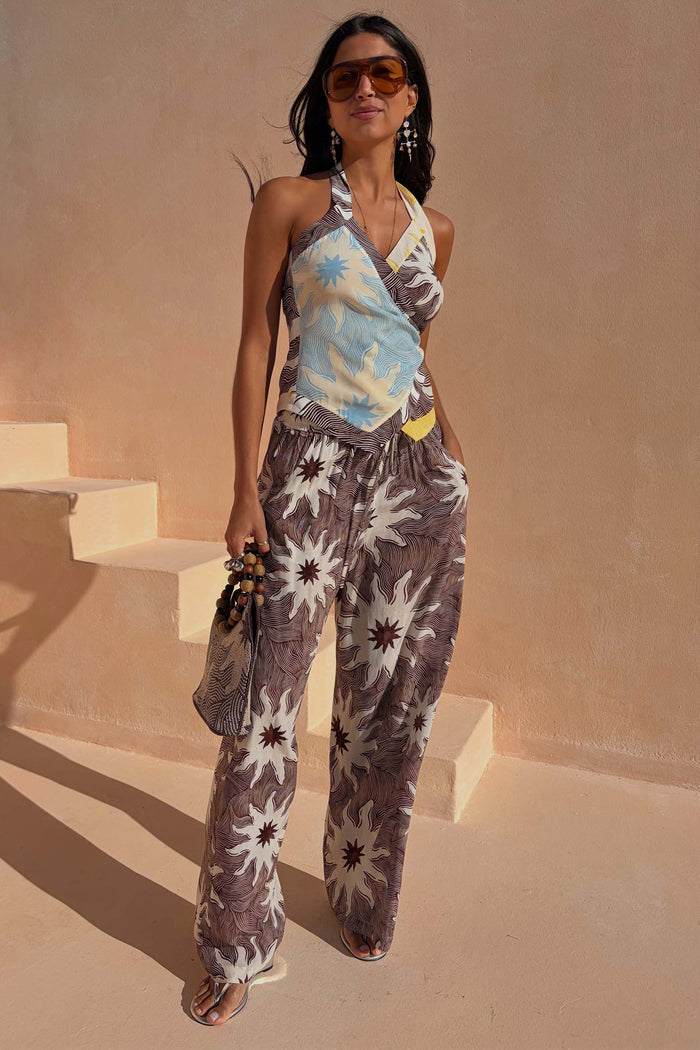 Multi-wear Soleil Wrap Top in chocolate with iconic sun motifs, styled with matching trousers for a summer co-ord.
