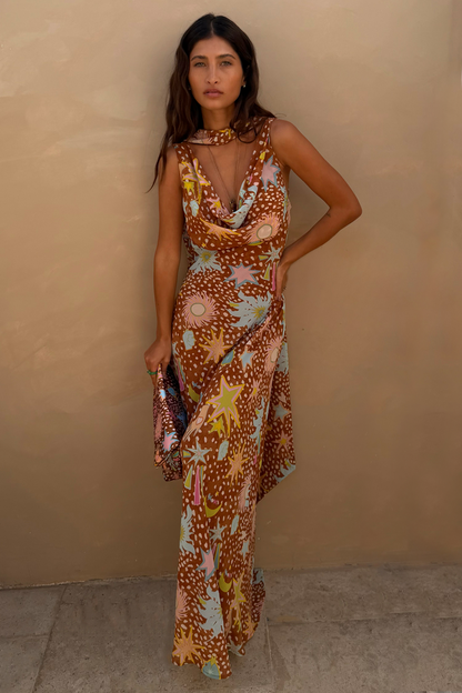 Star Fawn Sophie Dress in brown with sun and star motifs, featuring a draped neck, scarf, and clutch bag.