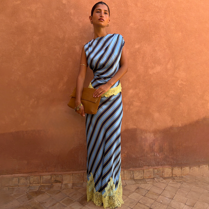 Blue diagonal stripe Maeva co-ord with yellow lace detailing and asymmetric top, set against a terracotta wall.