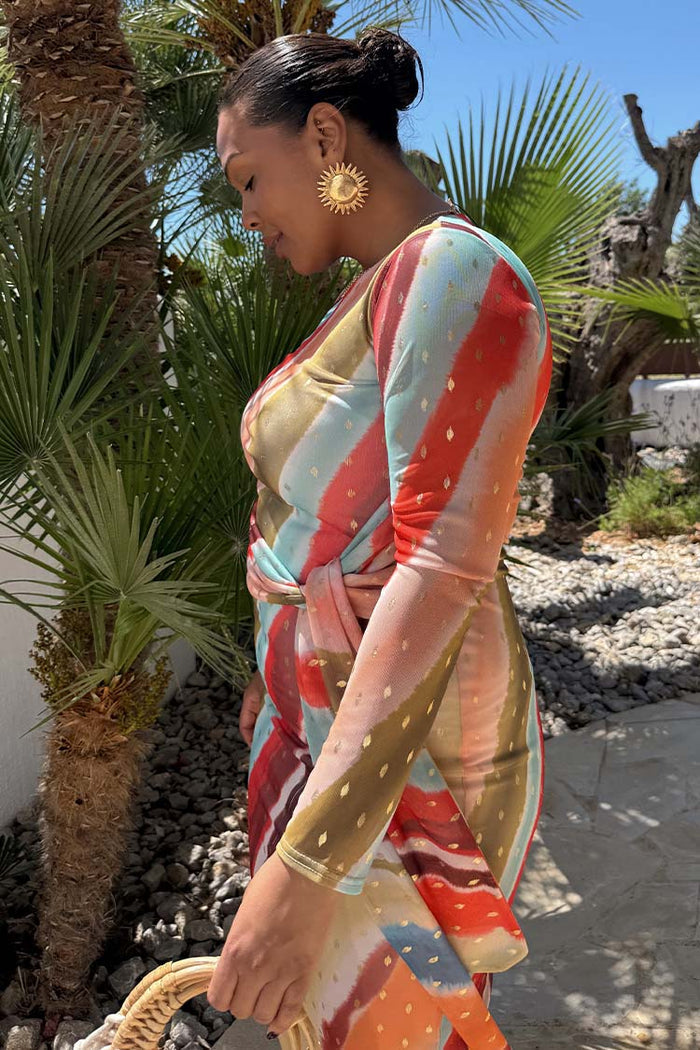 Sunset Stripe Mesh Midi Dress with a multicoloured stripe print and wrap tie waist in a vacation setting.