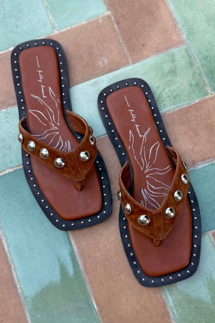 Tan Leather Stud Sandals with silver studs, square toe and flat black sole on a tiled background.