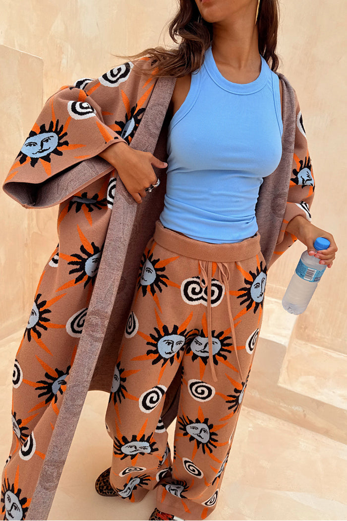 Tan Sun Trousers in a soft stretch knit with sun motifs, worn with a matching cardigan and a blue top.