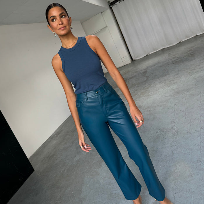 Model wearing Teal Vegan Leather Trousers in a straight leg fit, paired with a blue ribbed tank top.