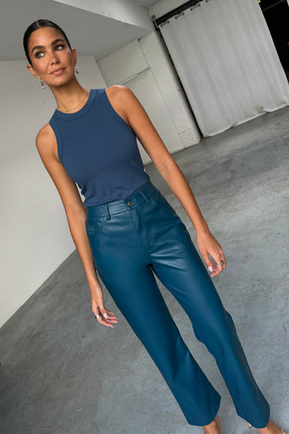 Teal straight leg vegan leather trousers and a navy ribbed tank top worn by a model.
