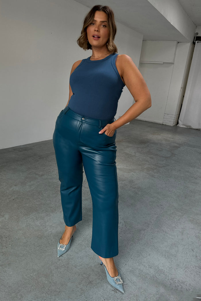 Teal Vegan Leather Trousers in a straight leg fit, paired with a blue tank top and embellished heels.
