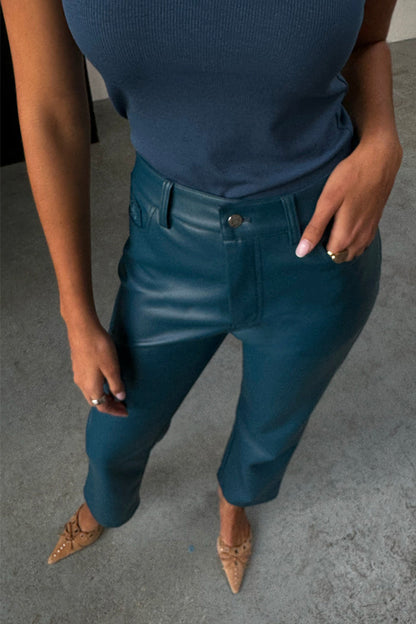 Teal Vegan Leather Trousers in a straight leg fit, styled with a blue ribbed tank top and pointed tan heels.