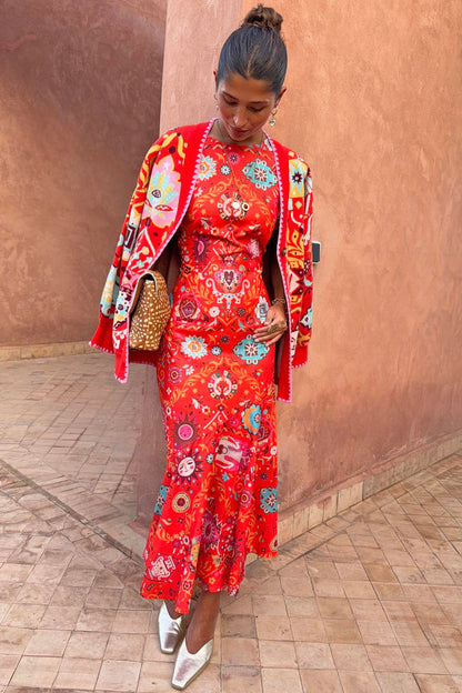 Tomato Tapestry Frida Dress in red with sun motifs, layered with a coordinating cardigan and metallic shoes.