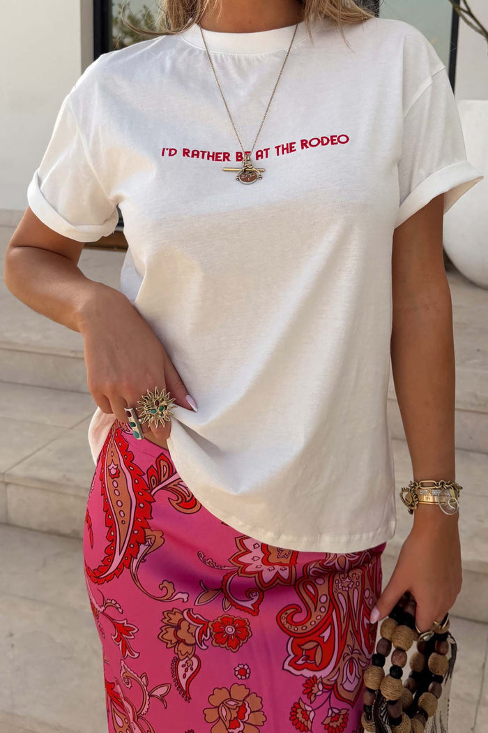 White cotton Rodeo T-Shirt with a red slogan and boxy fit, paired with a pink paisley print skirt.