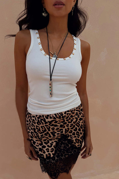 White ribbed vest with gold stud detailing along the neckline, styled with a leopard print lace skirt.