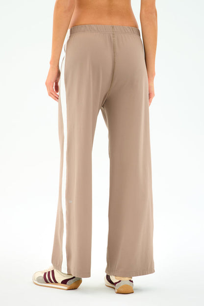 Model wears SPLITS59 Willow Airweight Wide Leg pants in Latte/White with maroon and white sneakers, shown from the back against a plain background.