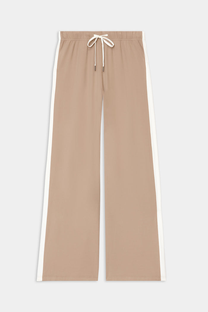 The Willow Airweight Wide Leg pants by SPLITS59 in Latte/White feature white side stripes and a drawstring waistband, crafted from a soft nylon-spandex blend, shown laid flat on a white background.