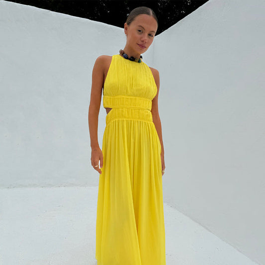 Yellow Ella Dress featuring pleat detailing, side cut-outs and a high neck on a model against a white wall.
