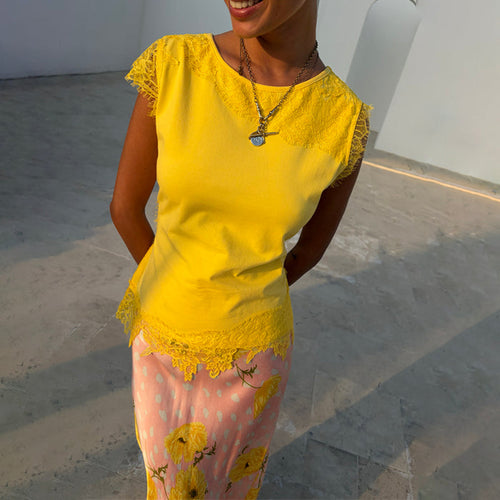 Yellow Lace Insert Top featuring lace cap sleeves and a scalloped asymmetric hem, styled with a patterned pink skirt.