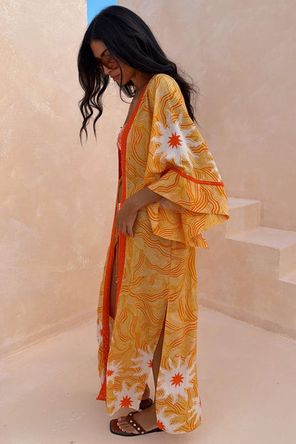 Yellow Sun Kimono in Soleil print with orange sun motifs, wide sleeves and side splits for vacation.