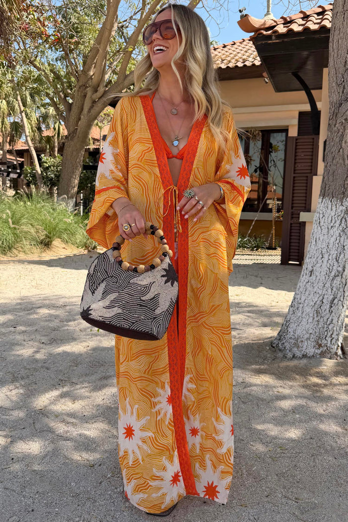 Yellow Sun Kimono in Soleil print with orange trim and sun motifs in a vacation setting.