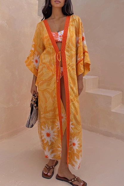 Yellow Sun Kimono in Soleil print with wide sleeves and orange trim, worn as a vacation cover-up.